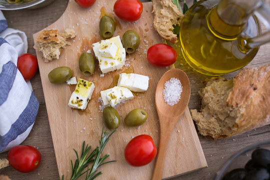 top view Greek cheese feta with virgin olive oil, green olives and fresh vegetables.