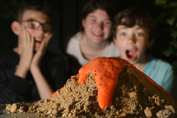 teenager kids boy and girl make chemical volcano trick experiment with vinegar soda and red paint close up photo