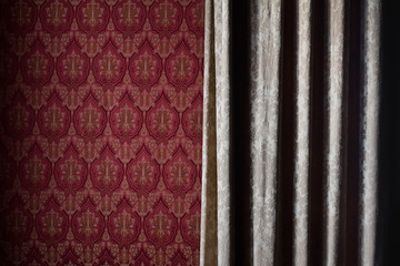 detail of curtain covering a red wallpaper wall