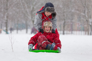 Two boys riding at the slide on snowy landscape