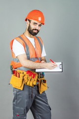 A builder in an orange helmet on a gray background signs something
