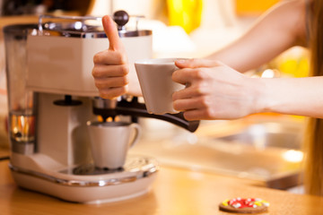 Obraz na płótnie Canvas Woman in kitchen making coffee from machine
