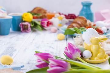 Easter breakfast flat lay with, bread toast with fried egg and gre, colored quail eggs and spring holidays decorations. Top view. Copy space. croissants for breakfast. Free space for text or postcard.