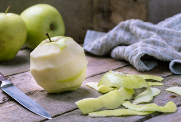 Green peeled apple on natural rustic wooden background.