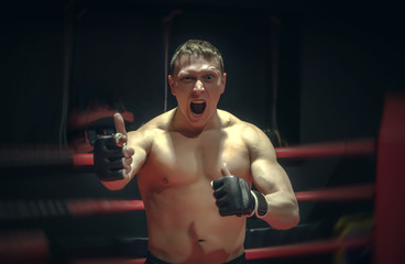 Fototapeta na wymiar Angry and aggressive fighter shows his superiority in the boxing ring. Indisputable champion concept. Calls for a fight.
