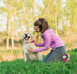 Pretty young woman with friendly golden retriever dog on the walk