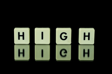 blocks with letters set on a glass table. Words arranged from letters on a glass substrate. The words high