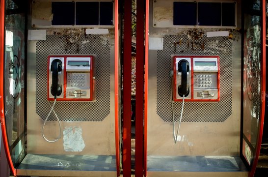 two retro red phones booth boxes close up, isolated  on sunny day technology of 20th century 