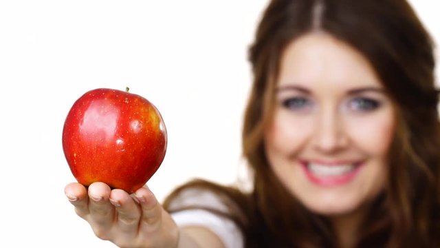 Young brunette woman recommend healthy eating diet, holding red apple in hand, focus on fruit, isolated on white.
