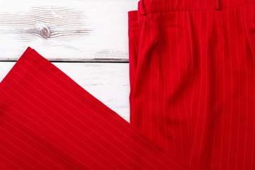 Feminine red classic trousers. Female clothes on wooden background. Women elegant style.