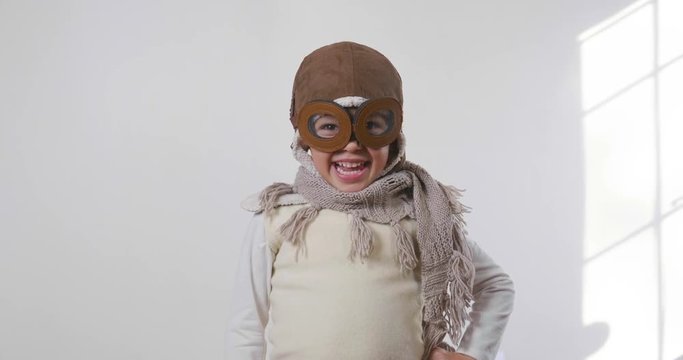 Portrait of a girl, dressed as a pilot or aviator with a hat and glasses, smiles looking at the camera as she dreams with open eyes and thinks about the future. Concept of: success, future, dreams