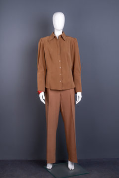 Mannequin in women brown suit. Female casual attire on dummy, grey background. Feminine office outfit.