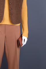 Female brown clothes and wallet. Close up female mannequin with waistcoat, sweater, trousers and purse. Female mannequin in mall.