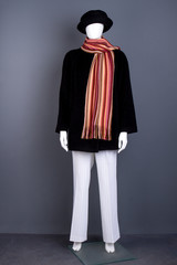 Female mannequin with black coat and scarf. Black women hat, overcoat, scarf and white trousers on mannequin. Feminine fashion style.