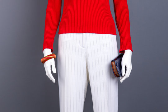 Mannequin with red sweater and accessories. Red pullover, white trousers, bracelet and wallet. Women modern style.