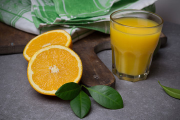 Glass of fresh orange juice with kitchen utensils on the dark stone table.