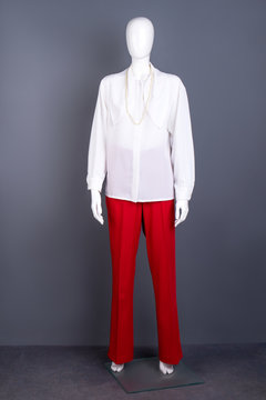 White blouse and red trousers for women. Full length female mannequin dressed in elegant long sleeve shirt with pearl necklace. Feminine classy outfit.