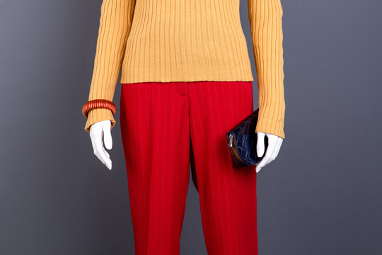 Mannequin in women clothes, cropped image. Close up female sweater and trousers on mannequin, grey background. Female classic apparel and accessories.