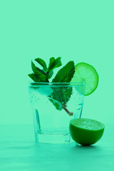 Mojito with lime and lemon and mint, cocktail with ice in a glass cup, soft drink with ice on a light background, empty space, cocktail pop art, toned background, summer drink, art