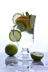 Mojito with lime and lemon and mint, cocktail with ice in a glass cup, soft drink with ice on a light background, empty space, cocktail pop art, toned background, summer drink, art