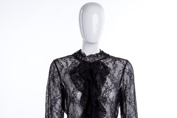 Female lace blouse with jabot. Female mannequin dressed in black lace blouse with frill collar, white background. Feminine elegance and style.