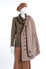 Beige cashmere coat for women. Female mannequin with headgear, sweater, skirt and overcoat. Collection of women autumn apparel.