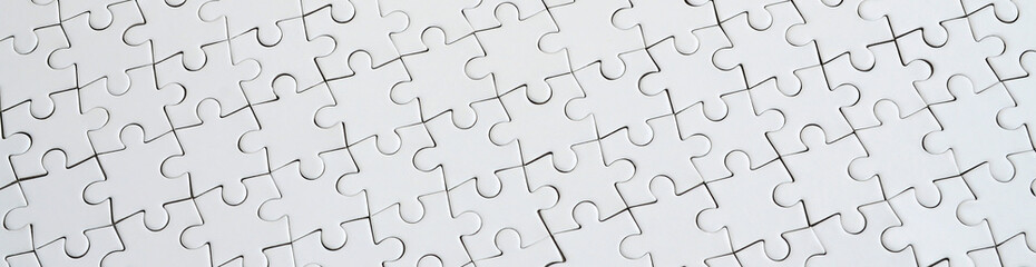 Close up texture of a white jigsaw puzzle in assembled condition. Top view. Many components of a...