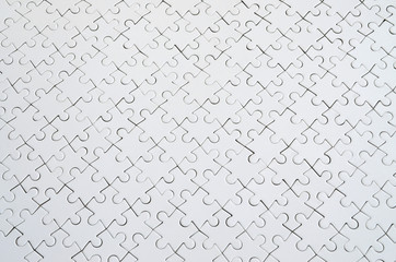 Close up texture of a white jigsaw puzzle in assembled condition. Top view. Many components of a...