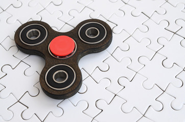 A wooden spinner lies on a white jigsaw puzzle background