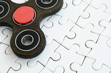 A wooden spinner lies on a white jigsaw puzzle background