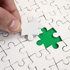 The human hand fills the last missing elements of the surface from the jigsaw puzzle. The concept...