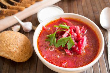 Traditional Ukrainian Russian vegetable soup borscht, with hard cream. parsley rye bread rolls, on black table