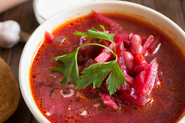 Traditional Ukrainian Russian vegetable soup borscht, with hard cream. parsley rye bread rolls, on black table