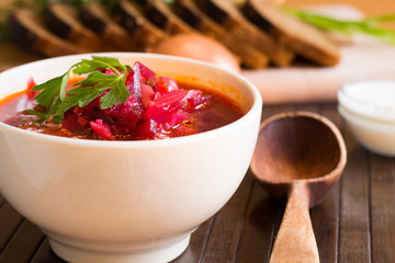 Traditional Ukrainian Russian vegetable soup borscht, with hard cream. parsley rye bread rolls, on black table
