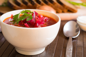 Traditional Ukrainian Russian vegetable soup borscht, with hard cream. parsley rye bread rolls, on black table