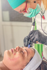 Beautician performs a needle mesotherapy treatment on a woman face.