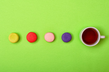 Colorful sweet macaroons and a cup of tea. Delicious breakfast. Top view.