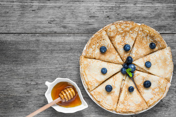 rolled traditional russian or ukrainian pancakes with fresh blueberries, honey and mint for breakfast
