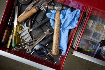 overhead view of toolbox full of tools and work gloves inside a workshop. 