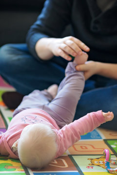 Father exercising the feet of his six months old baby girl