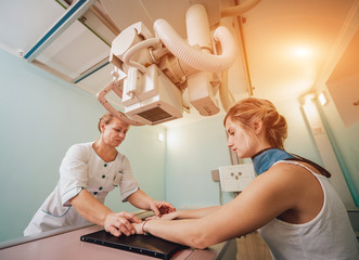 Radiologist and patient in a x-ray room. Classic ceiling-mounted x-ray system.