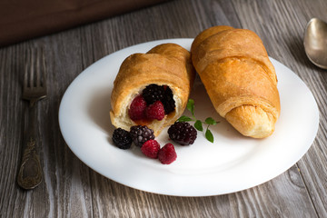 croissant on a large white plate on wooden table