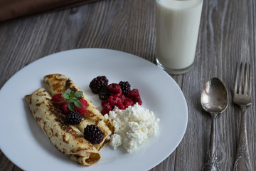 Crepes stuffed with cheese and strawberry topping on a white plate