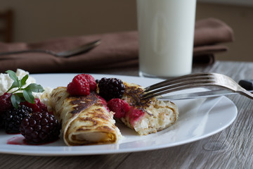 Crepes stuffed with cheese and strawberry topping on a white plate