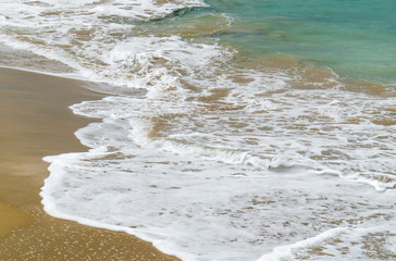 A close-up photo of a brown/Golden beach with waves in Sosùa, near Puerto Plata, Dominican Republic.