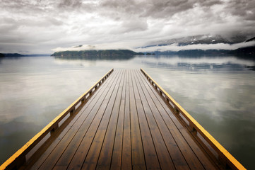 Wooden Dock on Harrison Lake, British Columbia, Canada. A dock appears to be heading out to nowhere on a lake in the Pacific Northwest. Harrison Hot Springs Resort.