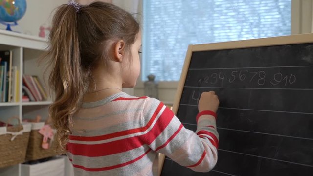 Early childhood development. Young mother explaining arithmetic to cute little daughter with blackboard at home. Play and learn. Slow motion