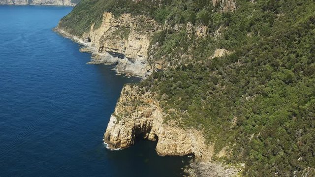 wide shot of a sea arch and the rugged cliffs at cape hauy on the three capes track in tasmania, australia