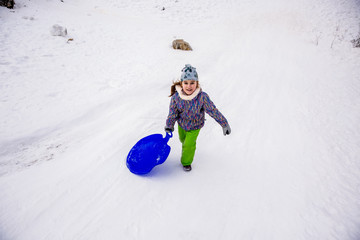 Fototapeta na wymiar girl sledding down snowy hill on sled fast speed