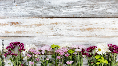 Mixed flowers forming bottom border on white weathered wooden boards